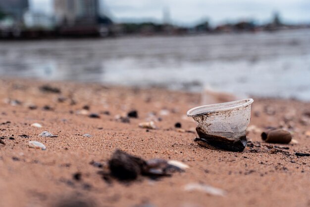 Vasos de plástico y basura en la playa de arena. Conciencia ambiental y plástica. Concepto del Día Mundial del Medio Ambiente. Salva la tierra salva la vida.