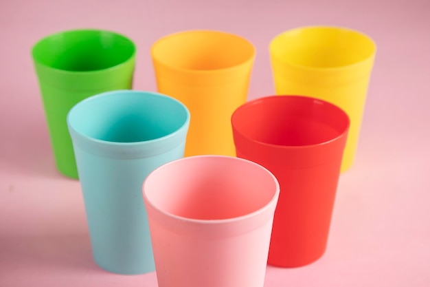 Vasos de plástico de color sobre fondo rosa