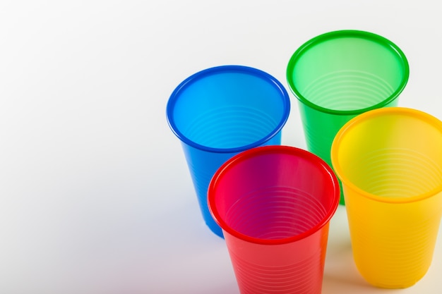 Vasos de plástico desechables multicolores aislados en blanco