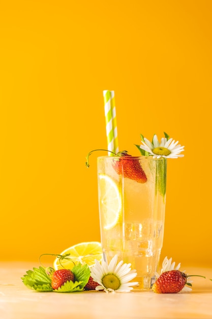 Vasos de refresco helado frío con limón y fresa. Fondo amarillo brillante