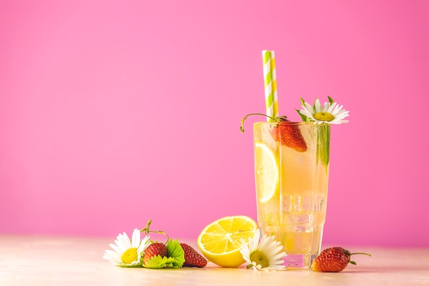 Vasos de refresco helado frío con limón y fresa. Fondo rosa brillante