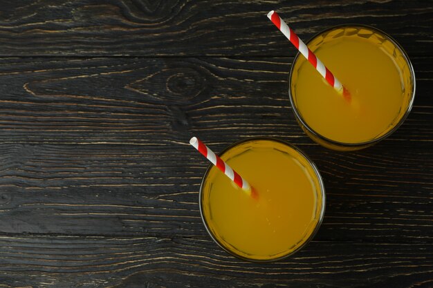 Vasos de refresco de naranja sobre superficie de madera