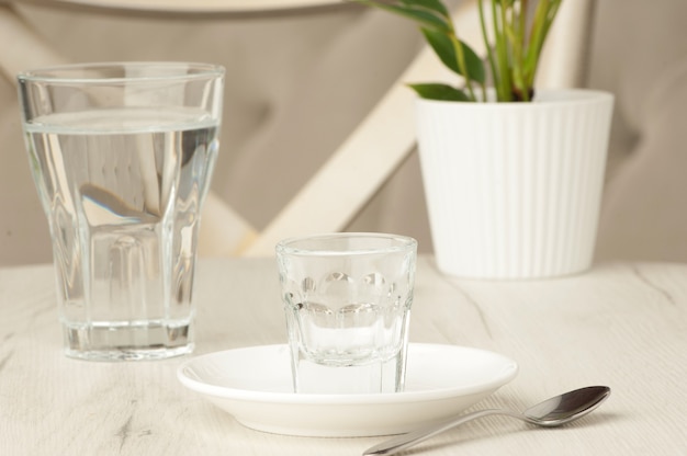 Vasos vacíos y una cuchara sobre una mesa blanca con una flor