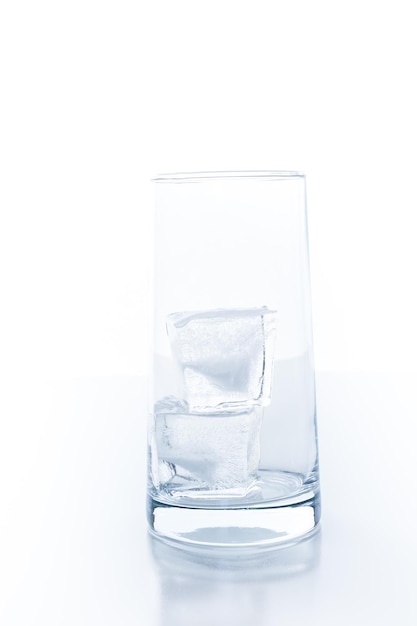 Vasos vacíos con grandes cubitos de hielo sobre un fondo blanco.