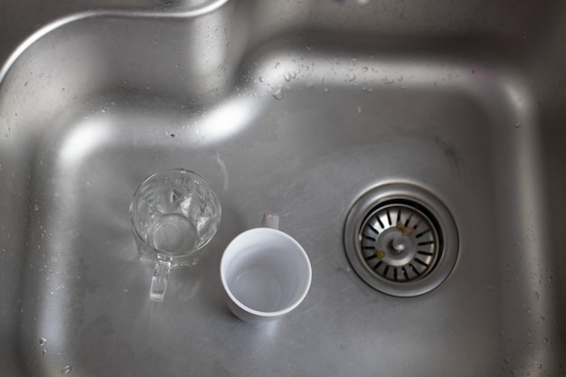 Foto vasos de vidrio y cerámica sucios en el fregadero, lavando