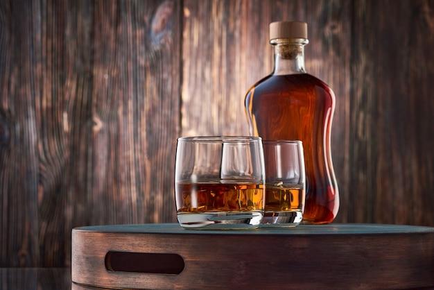 Vasos de whisky y una botella en la mesa de madera