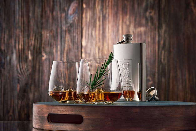 Vasos de whisky y un frasco sobre la mesa de madera