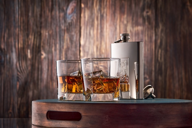 Vasos de whisky y un frasco sobre la mesa de madera