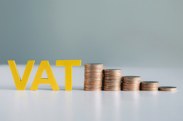 Vat concept.word iva e moedas empilhadas na mesa branca