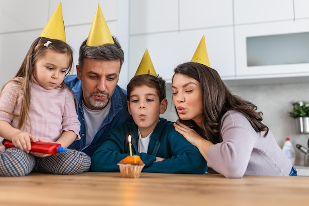 Foto vater bläst geburtstagskuchenkerzen in der küche aus und eine glückliche familie feiert einen geburtstag zusammen zu hause in der küchen