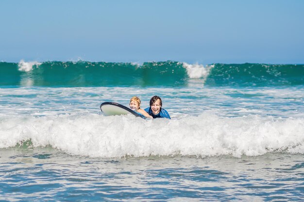 Vater bringt seinem kleinen Sohn bei, wie man im Urlaub oder im Urlaub im Meer surft. Reisen und Sport mit Kinderkonzept