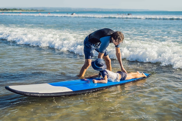 Vater bringt seinem kleinen Sohn bei, wie man im Urlaub oder im Urlaub im Meer surft. Reisen und Sport mit Kinderkonzept