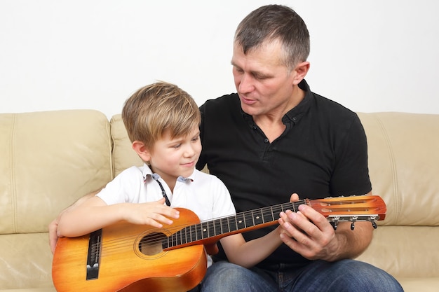 Vater bringt seinem Sohn das Gitarrenspielen bei