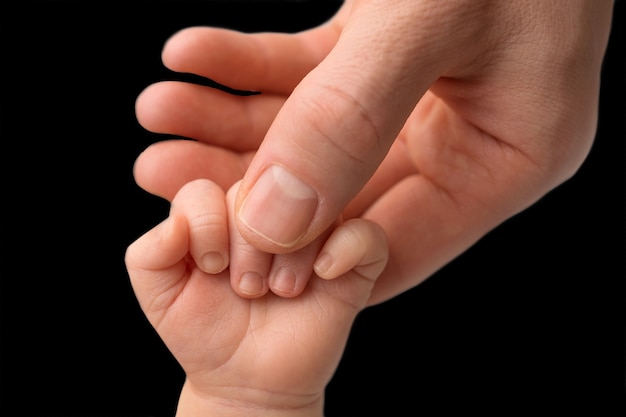 Vater, der die Finger des neugeborenen Babys hältNeugeborenes. Hand eines neugeborenen Babys. Hände von Eltern und Baby hautnah. Schwarzweißfoto. Foto in hoher Qualität