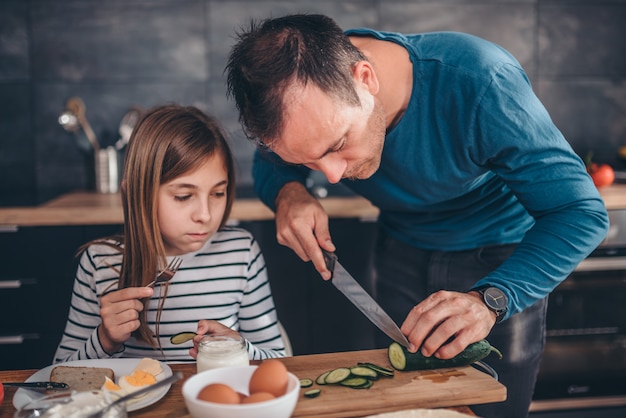 Vater, der Frühstück für Tochter zubereitet