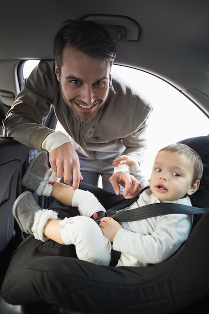 Vater, der sein Baby im Autositz sichert