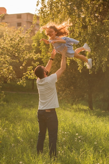 Foto vater, der seine tochter in der luft trägt