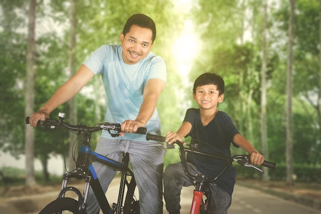 Vater fährt mit seinem Sohn Fahrrad im Park