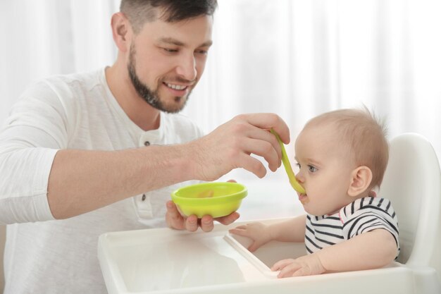 Vater füttert süße kleine Tochter zu Hause