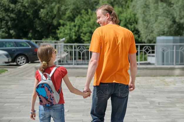 Vater geht mit seiner Tochter Händchen haltend