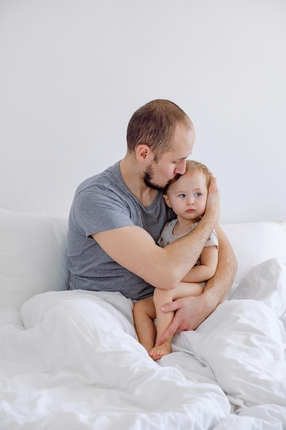 Vater hält Baby streichelnd tröstend und beruhigend sein Influenza-Krankheitskonzept Schlafzimmer