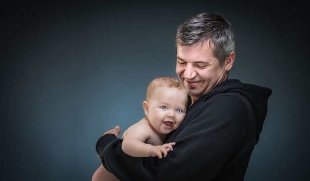 Vater hält ein Baby auf dunklem Hintergrund