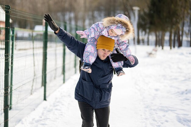 Vater hält Kind an sonnigen frostigen Wintertagen im Park auf den Schultern Vater und Tochter lieben