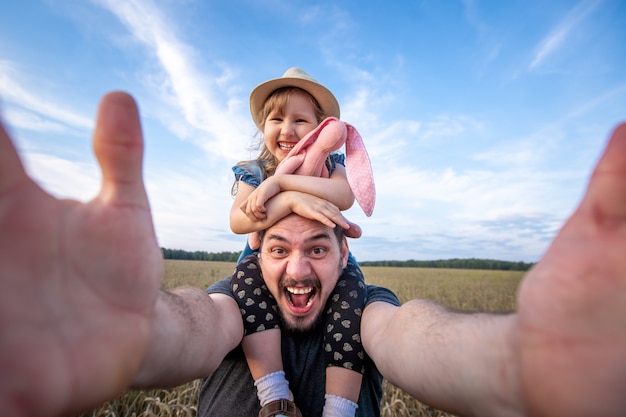 Vater hält seine Tochter auf seinen Schultern sitzen.