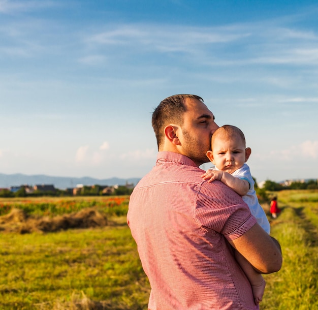 Vater hält seinen wunderbaren kleinen Sohn auf dem Feld auf Händen