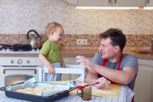 Vater hat Spaß daran, mit einem kleinen Kind zu spielen, während er zu Hause in der Küche kocht Vaterschafts- und Elternschaftskonzept