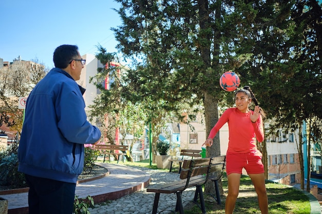 Vater hilft, seine Fußballspielerin Tochter mit einem Ball in Bolivien zu trainieren