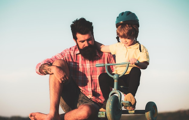 Vater hilft seinem Kind beim Fahrradfahren Schöner Vater, der Sohn beim Fahrradfahren unterrichtet