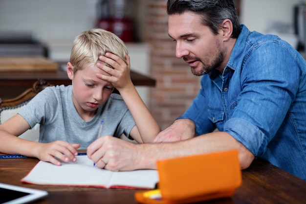 Vater hilft Sohn bei seinen Hausaufgaben in der Küche