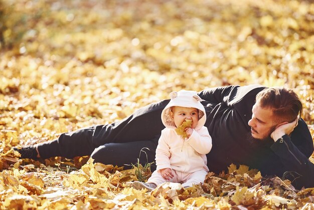Vater in Freizeitkleidung mit seinem Kind auf dem Boden liegend ist im schönen Herbstpark.