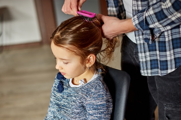 Vater kämmt, bürstet zu Hause die Haare seiner Tochter, Vater und Tochter lächeln