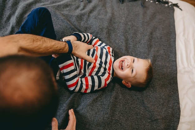 Vater kitzelt seinen Sohn auf dem Bett