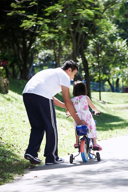 Vater lehrt seine Tochter im Park Fahrrad fahren
