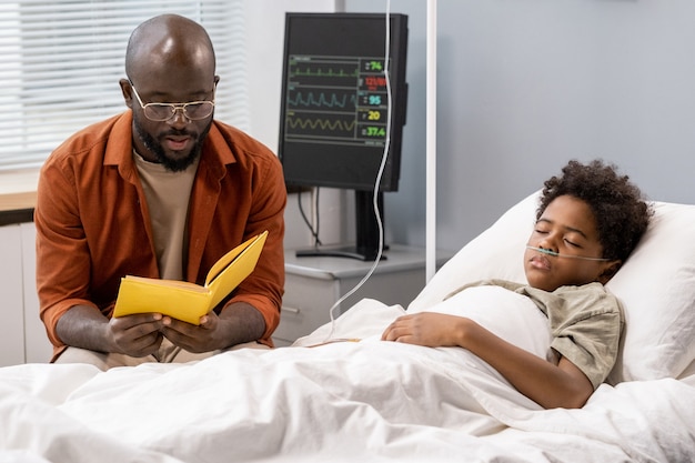 Vater liest seinem Sohn im Krankenhaus ein Buch vor