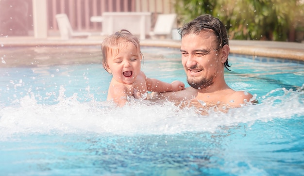 Vater mit einem Kind im Pool. Glückliche Eltern schwimmen mit Tochter im Pool