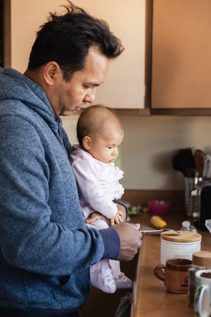 Vater mit einem kleinen Mädchen in der Küche, das am Morgen Kaffee kocht, Eltern- und Familienkonzept