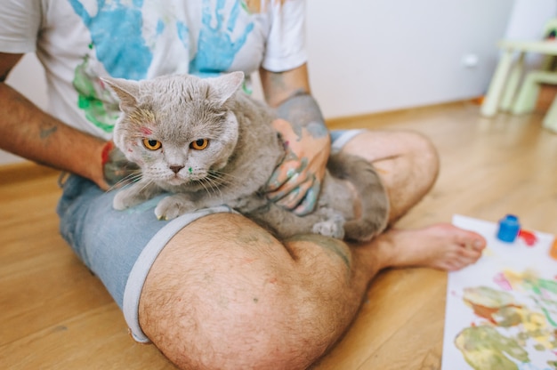 Foto vater mit einem sohn auf den schultern und einer katze an den händen bemalt mit farbe