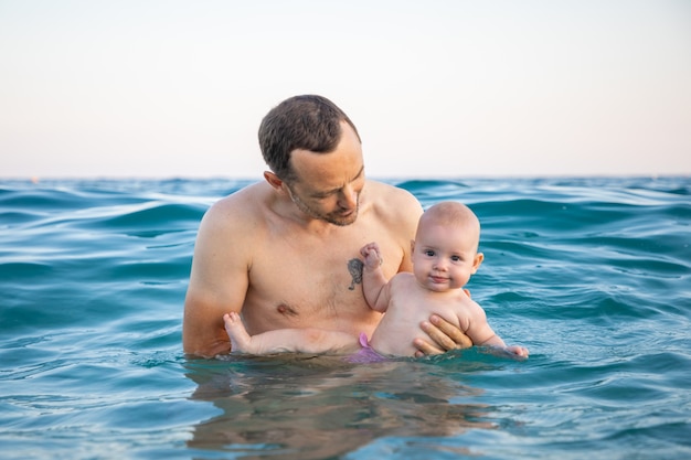 Vater mit ihrer Tochter, die zur Sonnenuntergangszeit im Meer schwimmt und sich entspannt