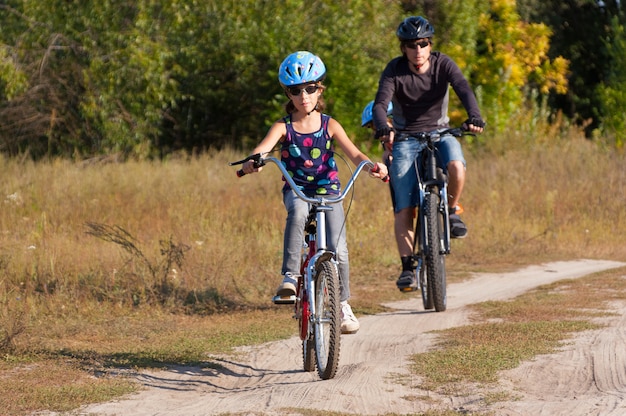 Vater mit Kindern, die draußen Fahrrad fahren