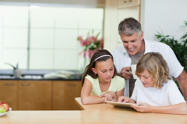 Vater mit Kindern und Tablette in der Küche