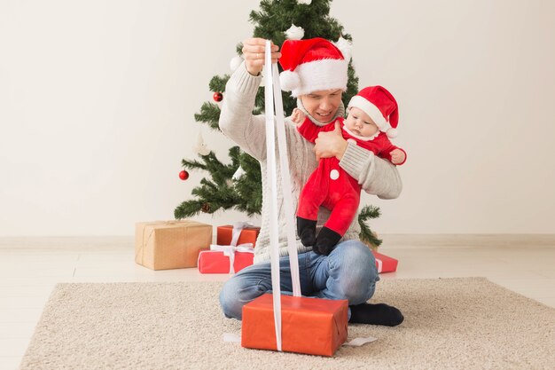 Vater mit seinem Baby, das Weihnachtsmützen trägt, die Weihnachten feiern.