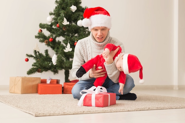 Vater mit seinem Baby, das Weihnachtsmützen trägt, die Weihnachten feiern.