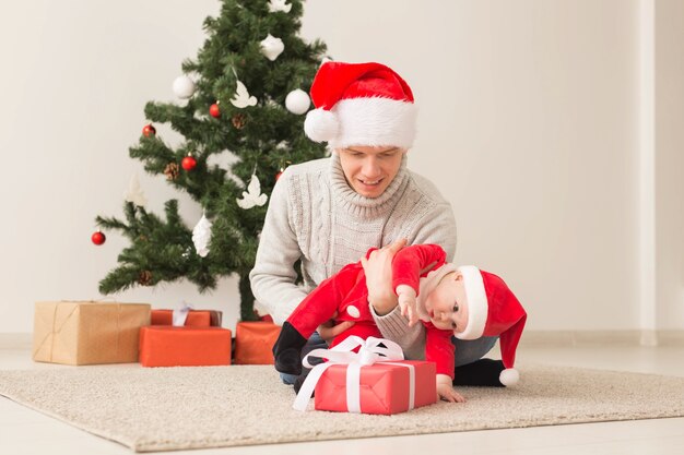 Vater mit seinem Baby, das Weihnachtsmützen trägt, die Weihnachten feiern.