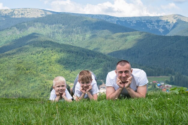 Vater mit Söhnen liegt auf dem Gras.