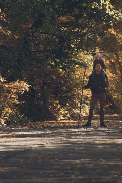 Vater mit Sohn auf seinen Schultern im Herbstpark spazieren.