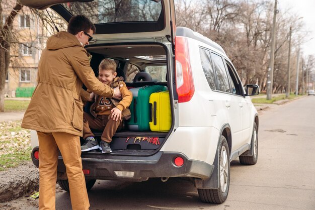 Vater mit Sohn, der Taschen zum Reisekonzept des Kofferraums packt